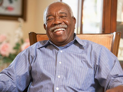 Man smiling and laughing while sitting in his favorite chair