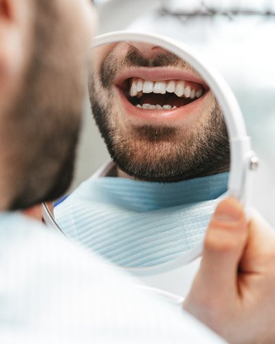 A man looking at his teeth in a mirror