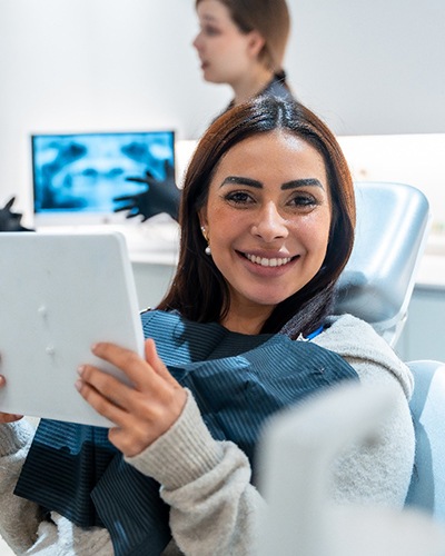 Woman smiling while holding mirror in treatment chair