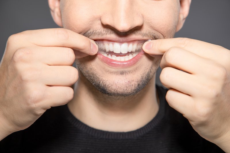 male whitening his teeth with strips
