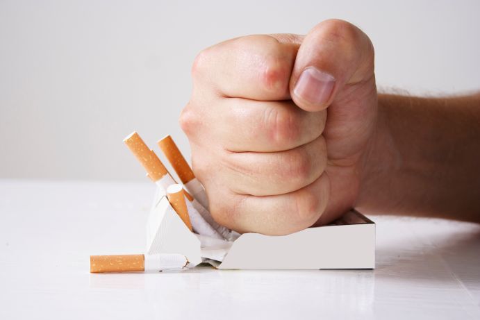 A fist crushing cigarettes