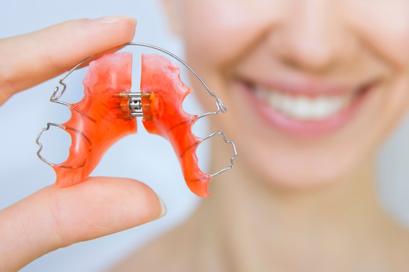 Patient holding retainer after Invisalign treatment
