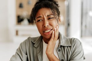 Woman touching hand to jaw in pain